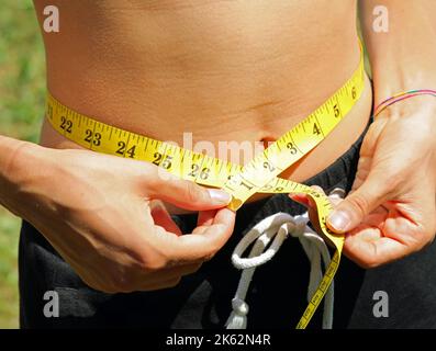 Anorexic Girl Measures With The Tape Measure Her Tight Waistline