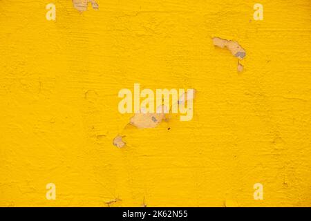 Facade of a house wall with yellow peeled paint as a background, a wall with yellow paint Stock Photo