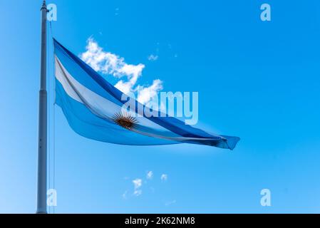 Argentine flag flying on a mast against a sunny blue sky. Argentina's national symbol Stock Photo