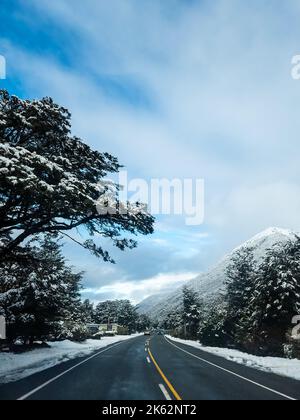 A vertical shot of a highway road in the snowy mountains in New Zealands Southern Alps Stock Photo