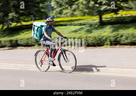 Courier On Bike Delivering Takeaway Food In City Stock Photo
