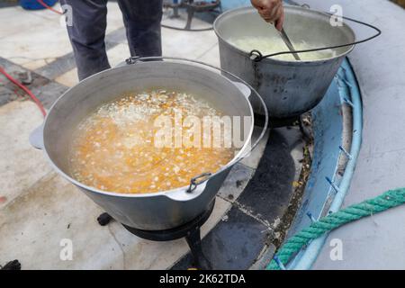 Shallow depth of field (selective focus) details with a big metallic cauldron in which a Romanian traditional fish soup (ciorba de peste) is being coo Stock Photo