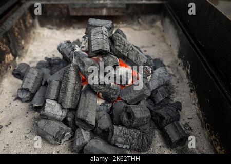 Shallow depth of field (selective focus) details with barbecue charcoal being lit up and prepared for cooking. Stock Photo