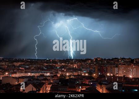 A scenic view of lightning hitting the ground near the city of Madrid during nighttime Stock Photo