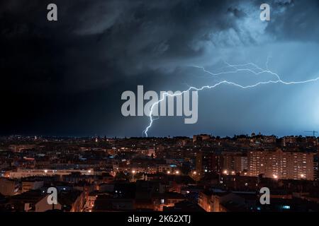 A scenic view of lightning hitting the ground near the city of Madrid during nighttime Stock Photo