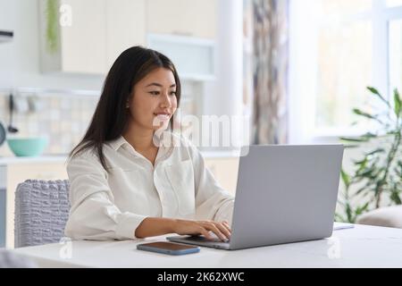 Young smiling asian student freelancer woman using laptop for remote work Stock Photo
