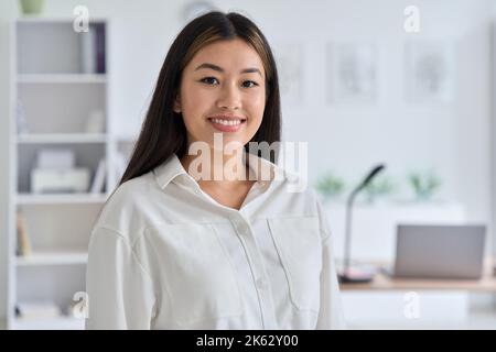 Indoor headshot portrait of young asian woman smiling looking at camera Stock Photo