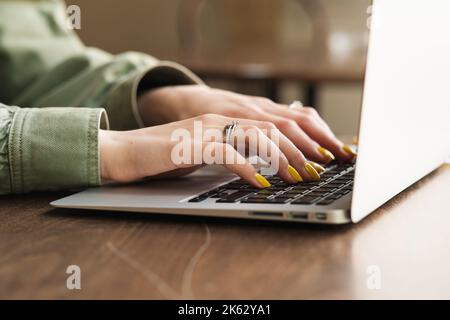 Close Up of Unrecognizable Woman Working on Laptop at a Cafe Table, Female Student Using Her Notebook for Study at Coffee Shop. Stock Photo