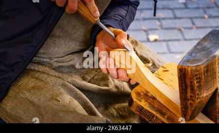 Hands carving spoon from wood, working with chisel close up. Process of making wooden spoon. Wooden workshop Stock Photo