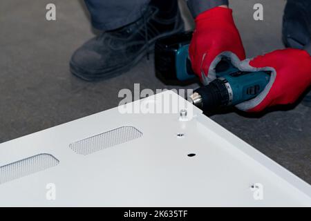 assembly of a metal structure in the workshop using a screwdriver Stock Photo