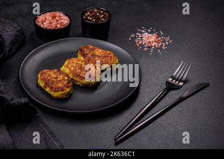 Diet vegetable cutlet from zucchini, carrot, herbs on a black plate on a dark concrete table. Healthy food Stock Photo