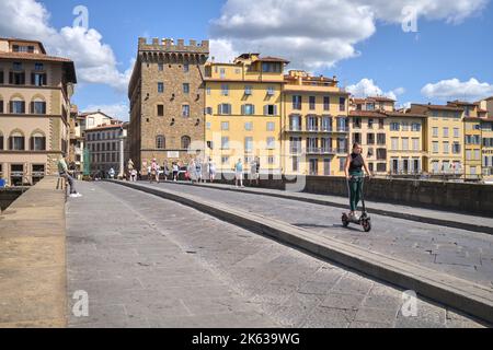 Girl on Escooter crossing Ponte Santa Trinita in Florence Italy Stock Photo