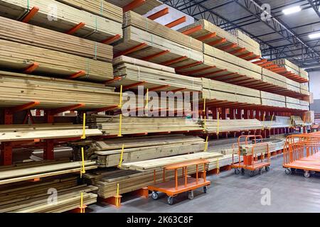 Warehouse with variety of timber for construction and repair on pallets on storage shelves. The factory for the production of laminate. Stacked wood Stock Photo