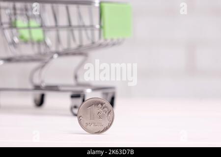 Mini shopping cart on table against brick wall background Stock Photo