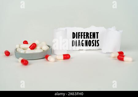 Medical concept. On a gray background, medical capsules and a paper plate with the inscription - Different diagnosis Stock Photo