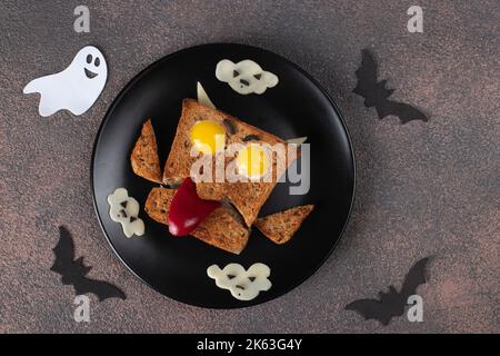 Ghost sandwich with sausage, quail eggs, sweet pepper and cheese on black plate on Halloween Stock Photo