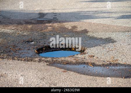 A dep pothole in asphalt parking lot filled with water Stock Photo