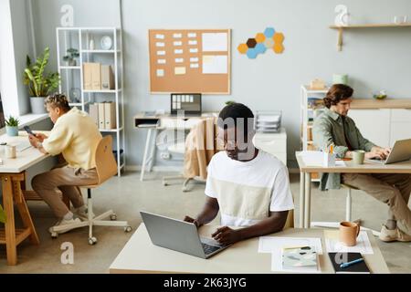High angle view at diverse team of business people working at separate desks in open office and using computers Stock Photo