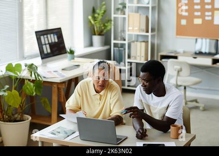 High angle portrait of two African American business people using laptop together in IT office and wearing casual clothes Stock Photo