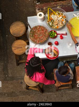Family eating lunch at the city market in Guanajuato, Mexico, tables and chairs, pico de gallo, sandwich, mother and son Stock Photo