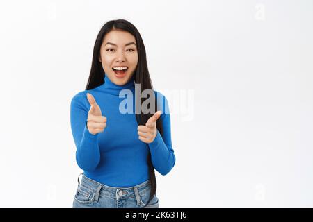 Portrait of enthusiastic beautiful female model, pointing fingers at herself and smiling, choosing, inviting you, congratulating, white background Stock Photo