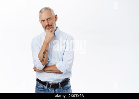 Thoughtful businessman looking down and thinking, pondering with serious face expression, making decision, standing over white background Stock Photo