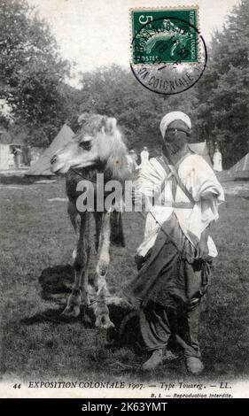 A Tuareg with his camel at The Colonial Exhibition at the 'Garden of Tropical Agriculture' at Nogent-sur-Marne, just outside Paris, France. The Tuareg people are a large Berber ethnic confederation. They principally inhabit the Sahara in a vast area stretching from far southwestern Libya to southern Algeria, Niger, Mali and Burkina Faso. Stock Photo