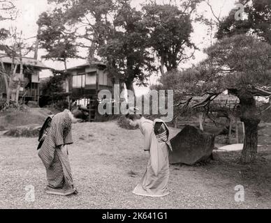 Vintage 19th century photograph: Two young Japanese women bowing to each other in greeting. Stock Photo