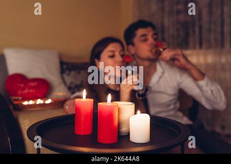 Young Valentines Day couple in love drinking champagne with strawberries having romantic dinner with candles celebrating at home at night Stock Photo