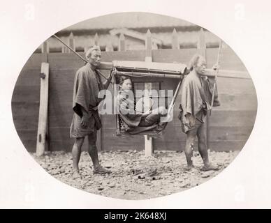 Vintage late 19th century photograph: Japanese woman in a kago, carrying chair, Japan, c.1870's. Stock Photo