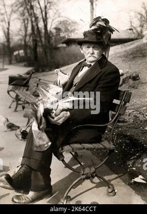 Early 20th century vintage press photograph - man feeding pigeons in Central Park, New York, c. 1920s Stock Photo