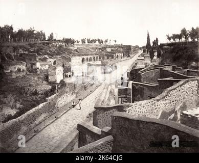 Vintage 19th century photograph - Street of Tombs, Pompeii, Italy. The Street of Tombs ran from the Herculaneum Gate on the road leading towards Herculaneum. It was forbidden to bury bodies inside the walls of Pompeii and so this street, which is outside of the city, has over thirty tombs in it. It was a busy road for travellers and so also had shops along it. Stock Photo