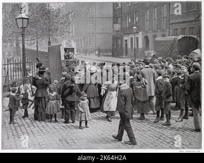 A group  of amused London children gather round to watch a traditional 'Punch and Judy,' show on a street corner in New Oxford Street entertained by Mr. J Bland. Stock Photo