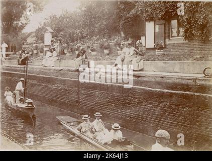 People boating on a canal, with spectators above them, possibly in Oxfordshire     Date: circa 1890