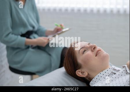A middle-aged woman lies on a couch and talks to a psychologist. Stock Photo