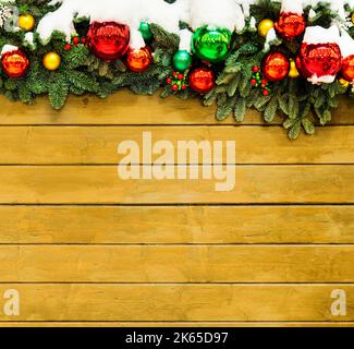 Old grunge wooden yellow board with Christmas border. wall with copy space. The old wooden wall is decorated with ice branches, red balloons and snow Stock Photo