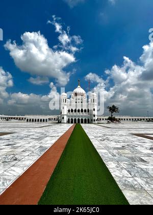 A vertical shot of Kartarpur Sahi with big white clouds above it in Shakargarh, Pakistan Stock Photo