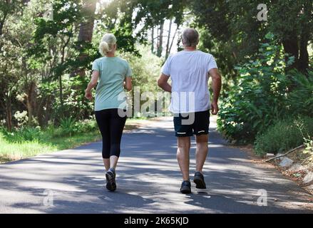 Running improves the overall functionality of your joints and bones. Rearview shot of a mature couple running together outdoors. Stock Photo