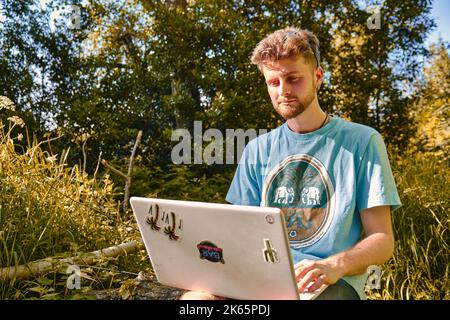 A young blond entrepreneur working outdoors on his laptop with a serious face Stock Photo