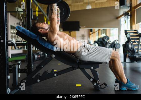 Profile of a strong man doing bench press exercises in a gym Stock Photo