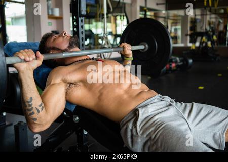 Strong man doing bench press exercises in a gym Stock Photo