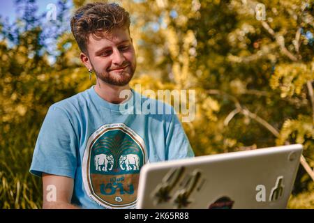 A young entrepreneur working outdoors on his laptop with a smiling face Stock Photo