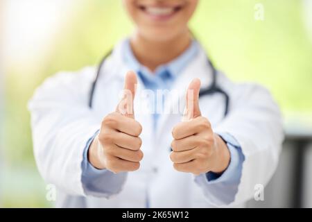 Unknown mixed race doctor making a thumbs up gesture while sitting in the office at work. Hispanic woman showing a good sign while sitting in a Stock Photo