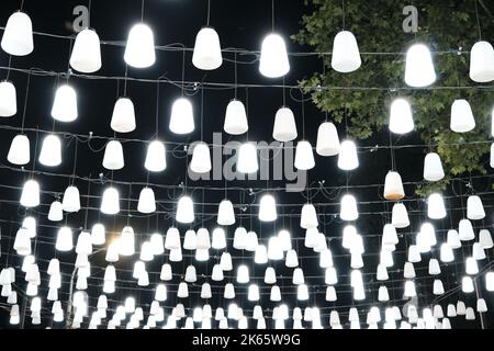 A garland with many decorative lanterns is hung on a night street, city street decoration Stock Photo