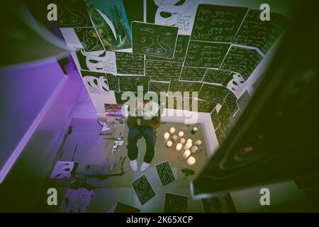 Above shot asian man with mental disorder sitting alone at night and feeling paranoid. Mixed race man mentally ill, feeling depressed and holding his Stock Photo