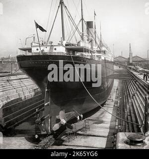 An early 20th century view of the 'Corinthian' in the dry dock (then the world's largest dry dock) next to the Albert dock on the  Liverpool waterfront, England. Built as a cargo and passenger liner for the White Star Line and Shaw, Savill & Albion Lin,e she was launched in 1902 from Harland and Wolff in Belfast. Stock Photo