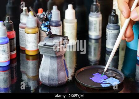 A person painting figures of warriors used to participate in role-playing games among various participants. Stock Photo