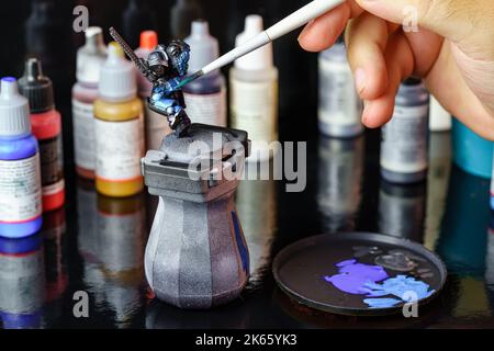 Person painting a small role-playing game figure for board games. Stock Photo