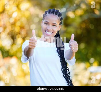 Im feeling brand new. a beautiful young woman showing thumbs up while standing outdoors. Stock Photo