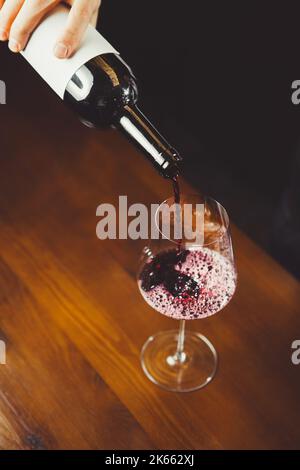 Close up shot of sommelier pouring red wine from bottle in glass Stock Photo